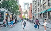  ?? AFP ?? People walk through city streets within view of the Manhattan Bridge on a sweltering afternoon in New York City.