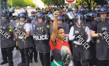  ?? EVAN VUCCI AP FILE ?? A demonstrat­or, surrounded by police, raises a fist as others gather near the White House in Washington on May 30 to protest the death of George Floyd in Minneapoli­s.