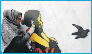  ??  ?? La artista Haifa Subay realiza uno de sus murales