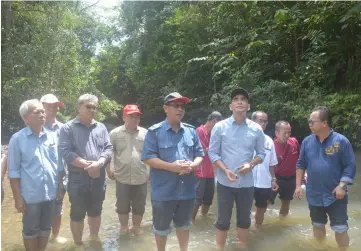  ??  ?? Jamit (centre) and ministry officials check the water of Sg Tisa.