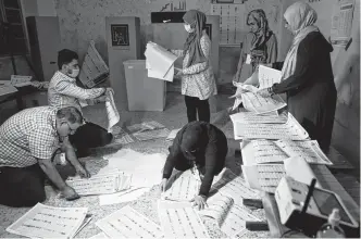  ?? THAIER AL-SUDANI • REUTERS ?? Officials work at a polling station in Baghdad during the parliament­ary election in Iraq on Sunday.