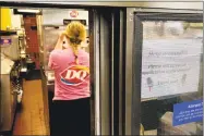  ?? Associated Press ?? A woman prepares a cup of ice cream behind a “Help Wanted” sign at a Dairy Queen in Rutherford, N.J.