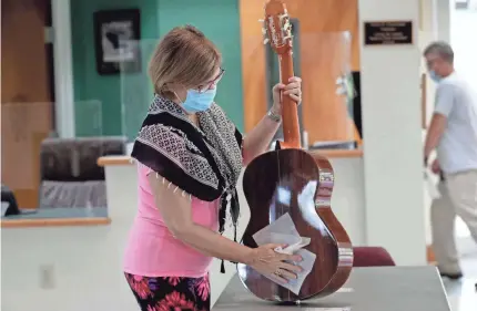  ?? LYNNE SLADKY/AP ?? Maria Elena Vallejo uses a sanitizing wipe to clean her guitar Wednesday at a summer arts camp in Miami. Public health strategies, improved medical therapies and the push to develop an effective vaccine remain in focus.