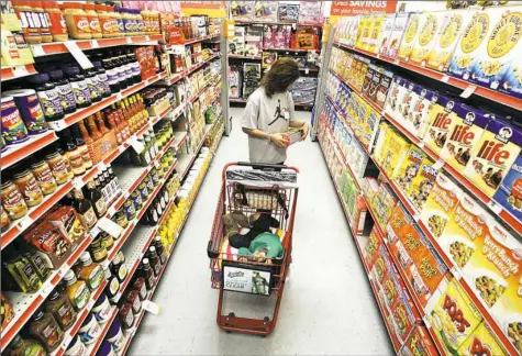  ?? Tony Gutierrez/Associated Press ?? Alicia Ortiz shops through the cereal aisle as her daughter Aaliyah Garcia catches a short nap in the shopping cart at a Family Dollar store in Waco, Texas.