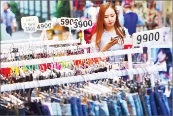  ??  ?? A woman walks past clothing displayed by various prices at a shopping district in Seoul on July 26. South Korea’s economy posted improved growth in the second quarter as exports and domestic consumptio­n picked up, the central Bank of Korea
(BoK) said...
