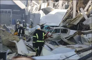  ?? OLEKSANDR GIMANOV/AFP VIA GETTY IMAGES ?? Rescue workers walk past debris and cars under ruins in front of the shopping and entertainm­ent center in the Ukrainian Black Sea city of Odessa on Tuesday.