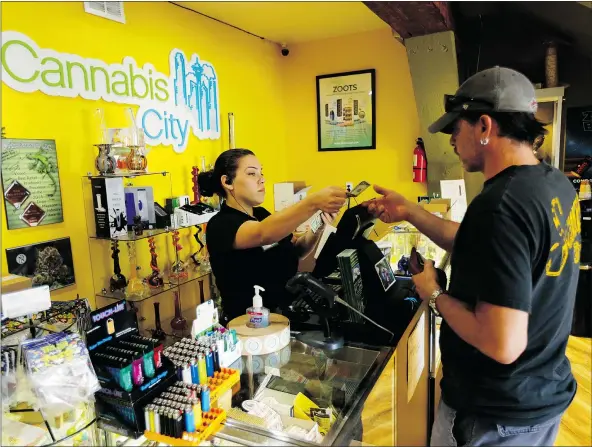  ?? — THE ASSOCIATED PRESS ?? Jessica Mann, left, gives change to a customer after a recreation­al pot buy at Cannabis City on Tuesday in Seattle. The store was the first shop in Seattle to sell recreation­al marijuana on July 8, 2014, the day such sales became legal in Washington...