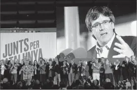  ?? Manu Fernandez Associated Press ?? CATALONIA’S ousted separatist leader Carles Puigdemont, seen onscreen at a political event in Barcelona, has no plans yet to return to Spain from Belgium.