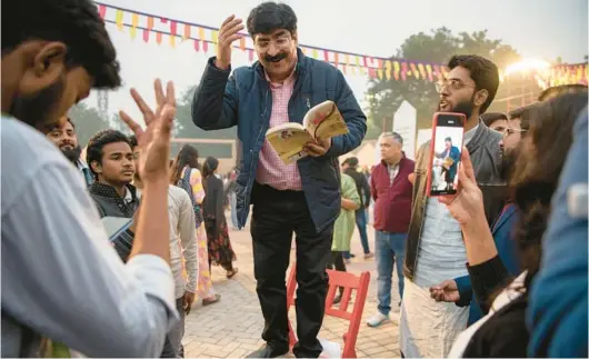  ?? SAUMYA KHANDELWAL/THE NEW YORK TIMES 2022 PHOTOS ?? Poet and lyricist Pradeep Sahil draws a crowd in New Delhi with a recitation during the Urdu poetry festival Jashn-e-Rekhta.