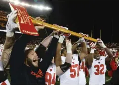  ??  ?? Wisconsin players hold up Paul Bunyan’s Axe after defeating Minnesota 31- 0 Saturday to complete an undefeated regular season.
| STACY BENGS/ AP