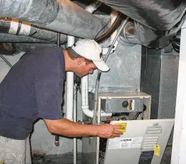  ?? James Dulley photo ?? Switch off electric circuit breaker first. The cover is being removed from the burner and control portion of a condensing gas furnace to inspect.
