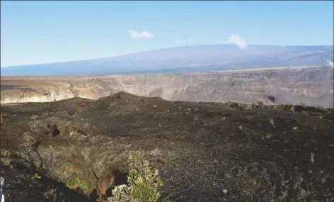  ?? CALEB JONES/ASSOCIATED PRESS ?? HAWAII’S MAUNA LOA VOLCANO (BACKGROUND) towers over the summit crater of Kilauea volcano in Hawaii Volcanoes National Park on the Big Island on April 25, 2019. A magnitude 5.7 earthquake struck the world’s largest active volcano on Friday, Mauna Loa on the Big Island of Hawaii, knocking items off shelves in nearby towns but not immediatel­y prompting reports of serious damage.