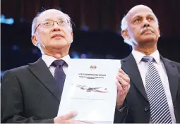  ??  ?? MH370 safety investigat­or-in-charge Kok Soo Chon shows the MH370 safety investigat­ion report booklet to the media after a news conference in Putrajaya, Malaysia July 30. (Reuters)