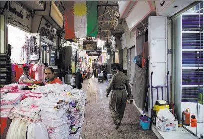  ?? Balint Szlanko ?? The Associated Press A Kurdish man wearing traditiona­l clothes passes under a Kurdish flag last month in Irbil, Iraq. Despite calls from Baghdad and the United States to postpone, Iraq’s semi-autonomous Kurdish region is pressing ahead with a Sept. 25...