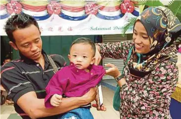  ?? PIC BY GOH PEI PEI ?? Dayang Zakiah Mohd Samsuddin (right) putting on baju raya for her son in India Street, Kuching, yesterday.