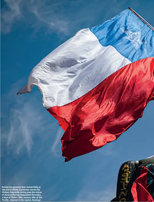  ??  ?? During the protests that rocked Chile at the end of 2019, a protester waves the Chilean flag while sitting atop the statue of General Manuel Baquedano Gonzalez, a hero of Chile’s 19th-century War of the Pacific, situated in the capital, Santiago