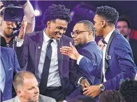  ??  ?? Kentucky’s De’Aaron Fox, center in top photo, is all smiles as he heads to the stage to be introduced after being selected fifth overall by the Sacramento Kings in the NBA draft Thursday night.