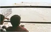  ?? PIC/NAVEEN SHARMA ?? People look at water flow from the Old Yamuna bridge which was temporaril­y closed for the traffic following the rise in the Yamuna water level in New Delhi on Monday