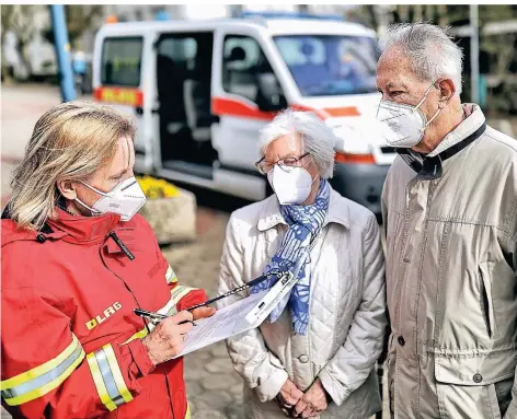  ??  ?? DLRG und AWO-Treff organisier­en Fahrten zum Impfzentru­m: Beate Peters (l.) notiert vor der Fahrt die Daten von Gitta und Gerd Hübner