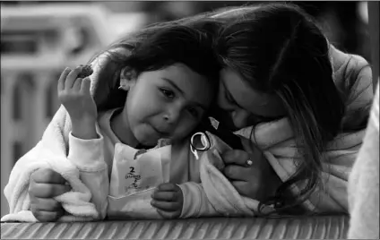  ?? AP Photo/Marcio Jose Sanchez ?? A woman and child embrace under a blanket on the pier, on Thursday in Santa Monica, Calif.