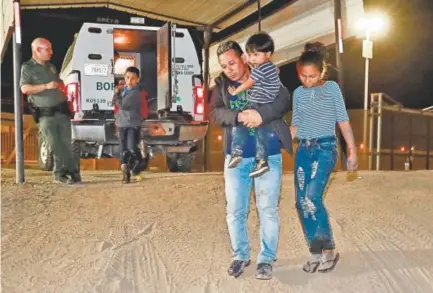  ?? Matt York, The Associated Press ?? A man carries his 3-year-old son as his daughter and his other son follow to a transport vehicle. The four were detained by U.S. Customs and Border Patrol agents last month in San Luis, Ariz.