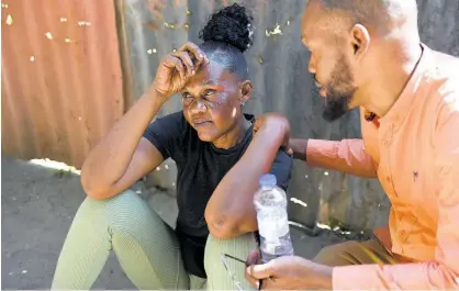  ?? RICARDO MAKYN PHOTOS ?? A grieving Andrea Williams is comforted by Raymond Pryce, the People’s National Party caretaker for St Catherine East Central, yesterday.