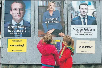  ?? AP PHOTO ?? Children walk past election campaign posters for French centrist presidenti­al candidate Emmanuel Macron and far-right candidate Marine Le Pen, in Osses, southweste­rn France, Friday. France will vote on Sunday.