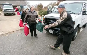  ?? J.T. WAMPLER NWA DEMOCRAT-GAZETTE ?? Dr. John Bakker, left, of Springdale, hands food bags to Joe Batlle of Farmington on Dec. 11, 2016. The food was then delivered to homebound seniors served by Farmington Senior Activity and Wellness Center. The gift bags were provided by Chase Family...