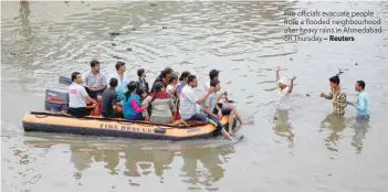  ?? Reuters ?? Fire officials evacuate people from a flooded neighbourh­ood after heavy rains in Ahmedabad on Thursday.—