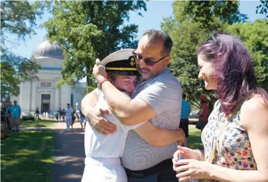  ?? BRIAN KRISTA/CAPITAL
GAZETTE ?? Above: Darby Graham, of El Paso, Texas, receives a
loving embrace from her father,
Mike, as her mother, Heather,
watches at the conclusion of Plebe Summer on Friday.
Top: It was nearly identical to a scene
captured on the front page of The Capital in August
1990, when Mike was photograph­ed hugging his mother,
Patricia.