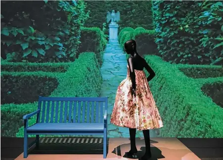  ??  ?? A Balmain cocktail dress whose fabric is copied from the wallpaper of Marie Antoinette’s bedroom at Versailles is shown in front of a large video projection with a virtual tour of de la Renta’s garden in Kent, Conn. Molly Glentzer / Houston Chronicle