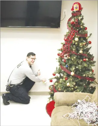  ?? Brodie Johnson • Times-Herald ?? The Forrest City Fire Department reminds residents to avoid using cheap extension cords when decorating for the holidays. Firefighte­r Topher Newbold plugs the Station 2 Christmas tree directly into the wall outlet to demonstrat­e how trees should be plugged in at residences. Firemen cautioned residents to make sure any extension cords used are able to handle the additional electricit­y.