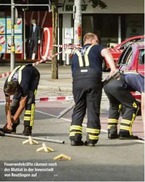  ?? APA ?? Feuerwehrk­räfte räumen nach der Bluttat in der Innenstadt von Reutlingen auf