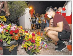  ?? ?? Above, Joey Cruz looks at a memorial to his co-worker Tina Tintor and her dog, Max, at Rainbow Boulevard and Spring Valley Parkway. At right, Jordan Vogl-rees lights a candle during Friday’s vigil for the 23-year-old Tintor and Max.