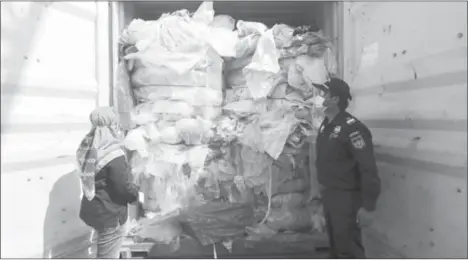  ?? — AFP photo ?? File photo shows Indonesian officers checking a container full with illegal imported plastics waste in Batam. Indonesia has returned seven shipping containers of illegally imported waste to France and Hong Kong, an official said.