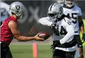  ?? JOHN LOCHER/THE ASSOCIATED PRESS ?? Las Vegas Raiders’ Derek Carr hands the ball off to Brandon Bolden on Friday at the team’s training camp in Henderson, Nev.