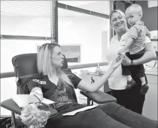  ?? Herald photo by J.W. Schnarr ?? Ashley Crabb tries to get her son, Ethan, to smile for the camera while she gives blood on Thursday, but Ethan really didn't seem to trust the photograph­er. Both Ashley and Ethan required blood transfusio­ns before and after Ethan was born.