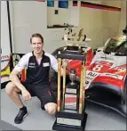  ?? Special to the Herald ?? Penticton’s Mark Houston proudly poses with the 24-hours of LeMans championsh­ip trophy, with the winning car in the background, in Cologne, Germany.