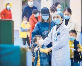  ?? GETTY-AFP ?? Children prepare to receive a COVID-19 vaccinatio­n last week in Wuhan, China. A vendor at a Wuhan animal market may have been the first person diagnosed with the virus.