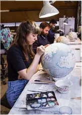  ??  ?? A watercolou­r artist paints detail on to a globe