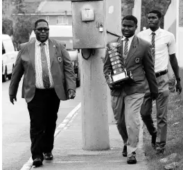  ?? FILE ?? Then vice-principal of Calabar High Calvin Rowe, with head boy Rajay Maragh, walks with the Mortimer Geddes Trophy on March 16, 2017. Rowe is now the acting principal. The school has won the boys’ title at Champs for seven straight years.