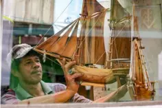  ??  ?? A man holding a replica of a Pinisi boat.