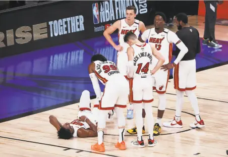  ?? Sam Greenwood / Getty Images ?? Miami’s Jimmy Butler lays on the court after tipping in a basket despite a Dwight Howard flagrant foul in the third quarter.