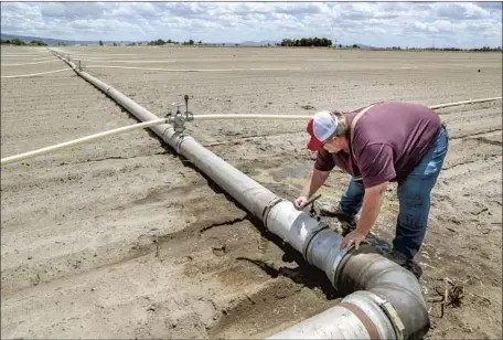  ?? Photograph­s by Robert Gauthier Los Angeles Times ?? MIKE McKOEN opens a valve to spray a field of onions as strong winds threaten to blow topsoil away. He fears for the future: “When people start looking down the barrel of foreclosur­es ... when their livelihood­s are drying up and going away, what choices do they have?”