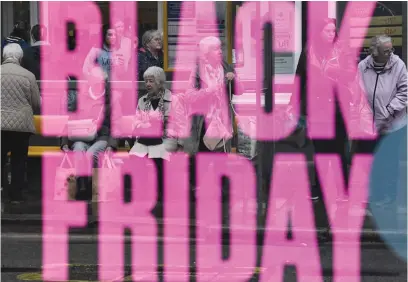  ?? Picture : AFP ?? AD POWER. People waiting at a bus stop are reflected in a Black Friday sign in Chester in Britain last week.