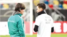  ??  ?? Germany head coach Joachim Loew (L) talks to midfielder Mesut Ozil during a training session last March. Ozil quit internatio­nal duty in July, citing racism and disrespect within the German FA (DFB) and has reportedly broken contact with Loew. - AFP photo