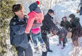  ?? PAUL CHIASSON / THE CANADIAN PRESS FILES ?? Somalian refugees are helped across the border into Canada last February near Hemmingfor­d, Que. Many recent migrants crossing illegally into Canada are Nigerian, which suggests word-of-mouth about Canada as a safe haven has continued to spread.