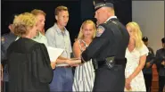  ?? PHOTO COURTESY OF UPPER GWYNEDD POLICE DEPARTMENT ?? Longtime Upper Gwynedd Det. Sgt. Ted Caiola, center, receives an oath from District Judge Suzan Leonard promoting him to the rank of Deputy Chief, while family members and fellow officers look on during a department promotion ceremony on July 22.