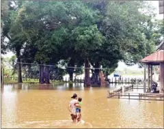  ?? SUPPLIED ?? A mother navigates a flooded area with her child in August after water levels rose due to heavy rains and the closing of Lower Sesan II Hydropower Dam’s gates in Stung Treng province.