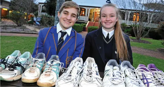  ?? PHOTO: JOHN SESSARAGO ?? MANY SHOES: Toowoomba Grammar School’s Adrian Irwin and Fairholme College’s Libby Stumer with shoes collected for children in Zambia.